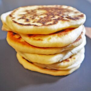 Homemade fluffy pita bread stacked on a serving plate.