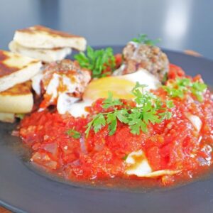 Hearty shakshuka with vegetarian meatballs and poached eggs in a tomato sauce, served with pita bread.