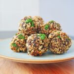 Homemade vegetarian mushroom meatballs served on a moss colour plate with fresh herbs.