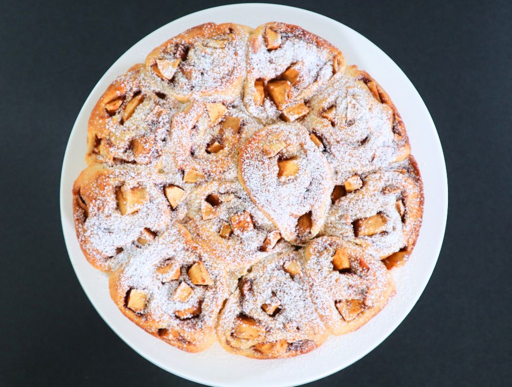 Fluffy homemade apple cinnamon bread rolls arranged in a round serving dish.