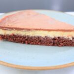 A slice of Chantilly and chocolate cake and chocolate ganache served on blue round plate.