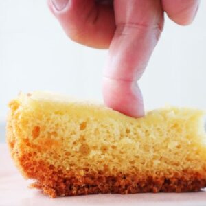 Fluffy sponge cake made in a pressure cooker, sliced with finger pressing on it.