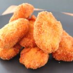 Crispy homemade chicken nuggets served stacked on a black plate