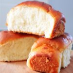 three freshly baked milk bread stacked over wooden board