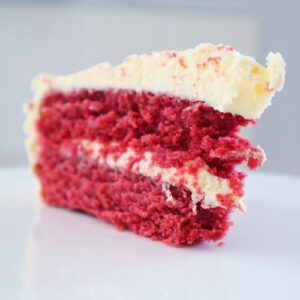 Moist red velvet cake slice topped with cream cheese frosting
