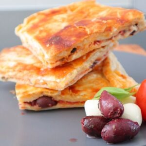 stacked on a plate with olives and cheese slices of rustic pizza