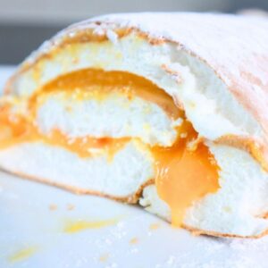 Sliced Brazo de Mercedes with creamy condensed milk filling and powdered sugar on top