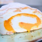 Sliced Brazo de Mercedes with creamy egg condensed milk filling and powdered sugar on top rolled up