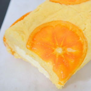 orange cake roll over white serving board