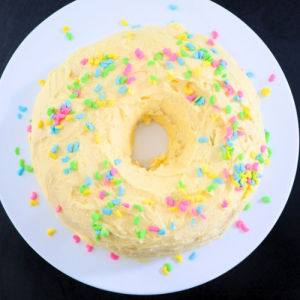 frosted round cake with sprinkles on round serving tray